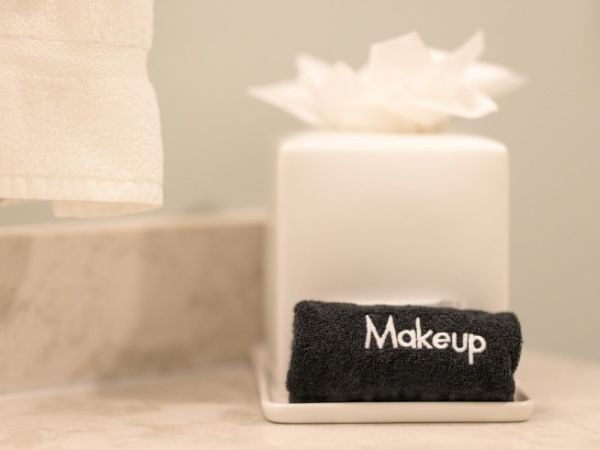A small white tray holds a black towel labeled "Makeup" next to a white tissue box on a bathroom countertop.