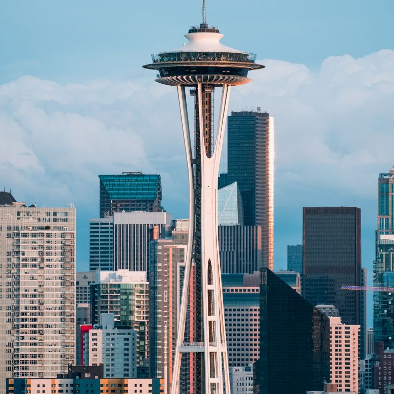 This image features the Space Needle, a famous observation tower, with the Seattle skyline in the background and partially cloudy skies above.